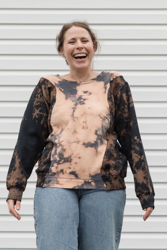 person wearing bleached sweater, upcycled in canada and featuring the 'no labels, just vibes.' embroidery