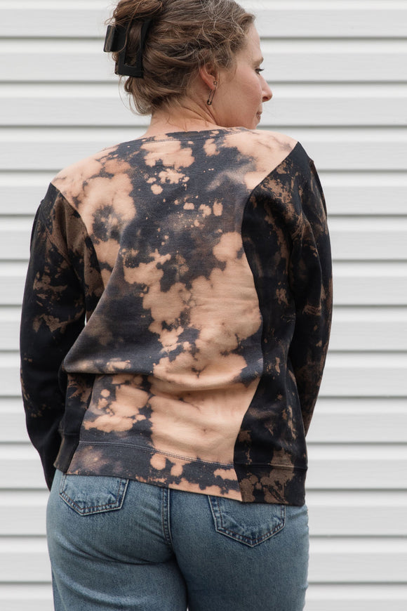 person wearing bleached sweater, upcycled in canada and featuring the 'no labels, just vibes.' embroidery