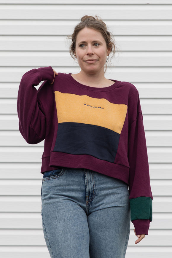 person wearing burgundy, gold, navy and green sweater, upcycled in canada