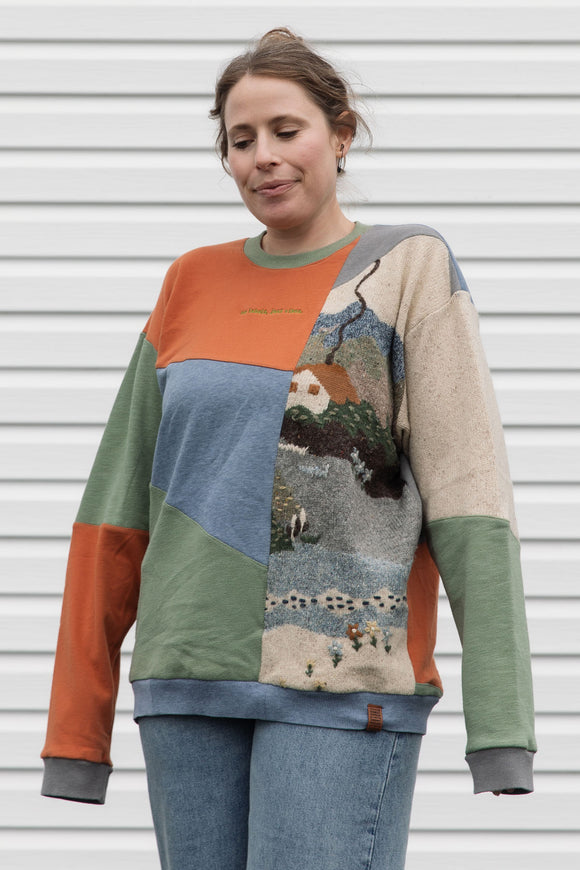 person wearing a one-of-a-kind patchwork sweater, featuring a knit cottage motif, upcycled in canada