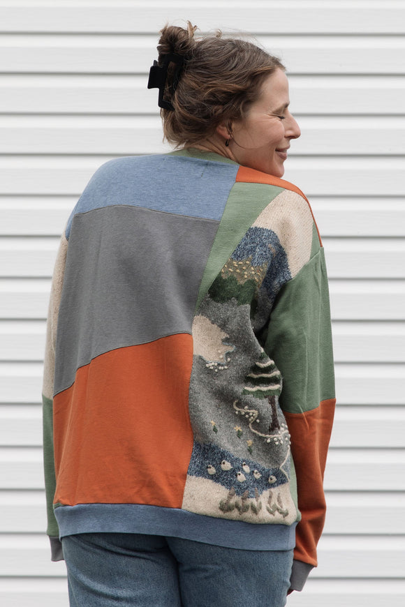 person wearing a one-of-a-kind patchwork sweater, featuring a knit cottage motif, upcycled in canada