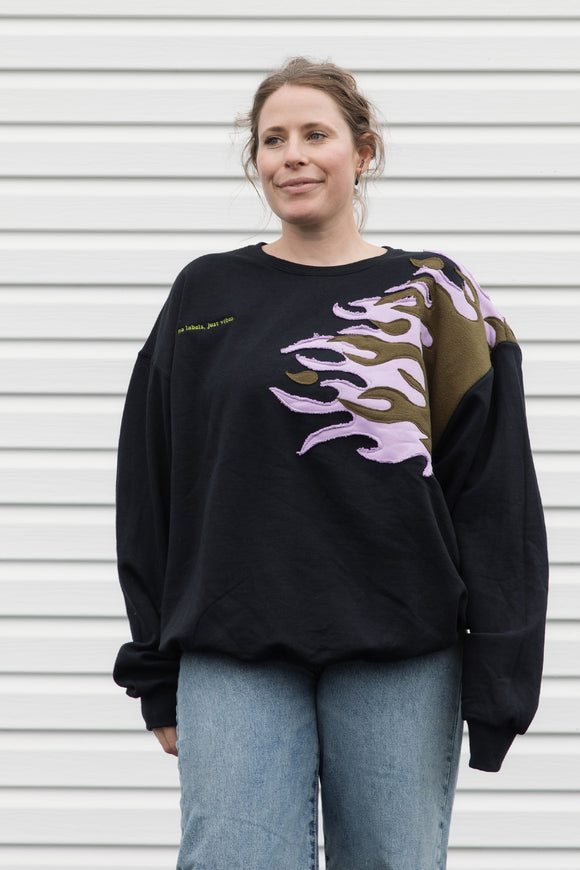 person wearing a black sweater with graphic flames in purple and green, upcycled in canada