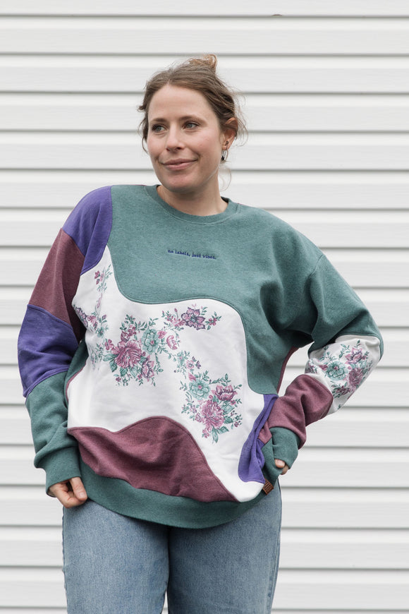 person wearing colourful flower sweater. Purple, Maroon and Green floral motif, upcycled in canada