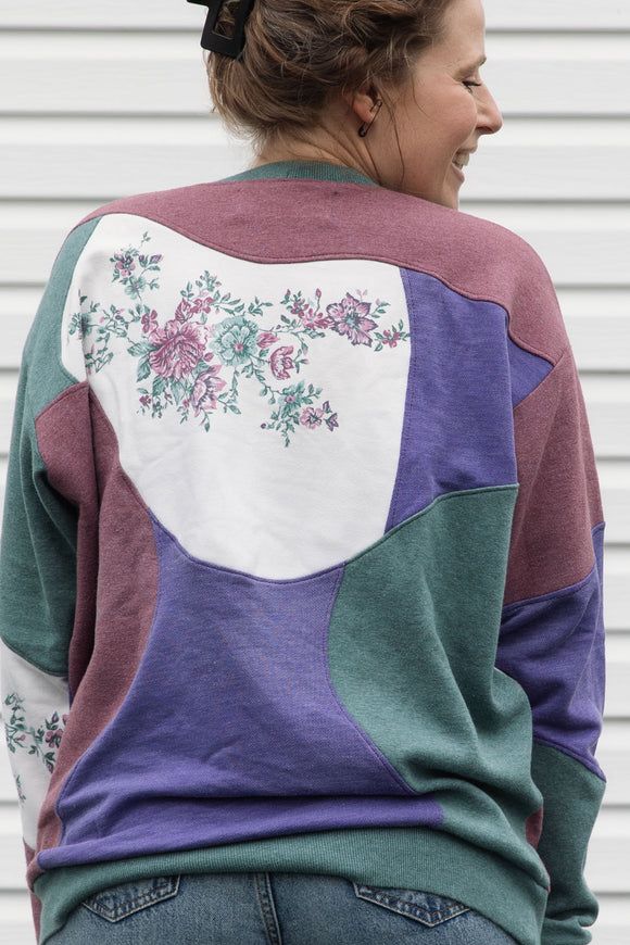 person wearing colourful flower sweater. Purple, Maroon and Green floral motif, upcycled in canada