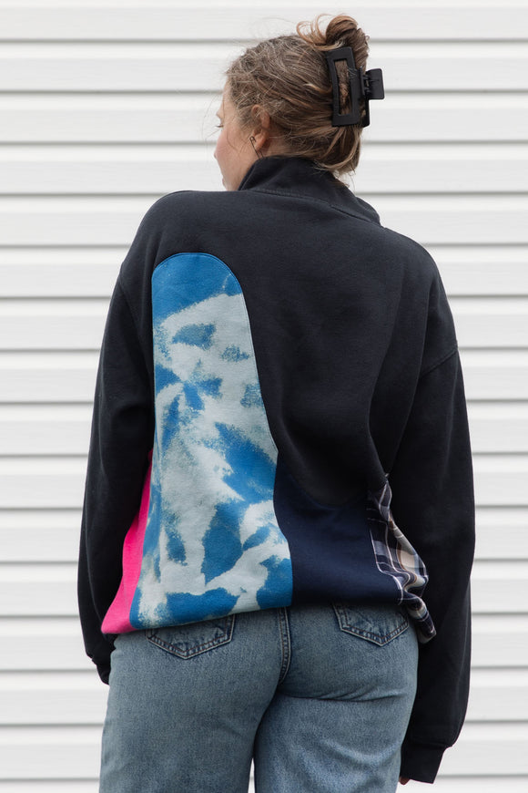 person wearing black half zip with lots of colour details and patterns, upcycled in canada