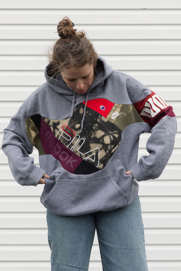 Person wearing a gray hoodie with colorful brand logos, upcycled in canada