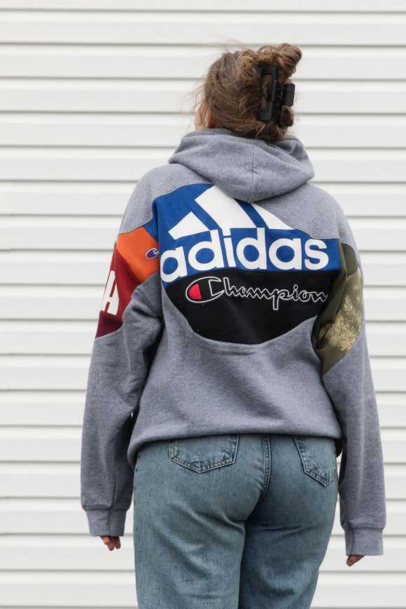Person wearing a gray hoodie with colorful brand logos, upcycled in canada