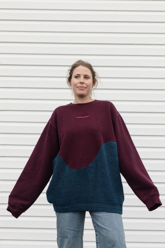 Person wearing a two-tone sweater with maroon and blue sections upcycled in canada