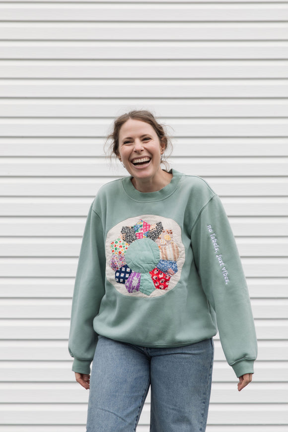 person wearing a mint green sweater with quilted pinwheel on the front, upcycled in canada