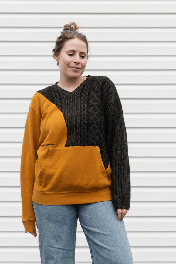 Person wearing a two-tone sweater with mustard yellow and black, upcycled in canada