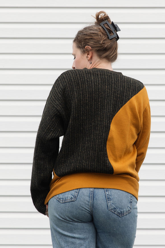 Person wearing a two-tone sweater with mustard yellow and black, upcycled in canada