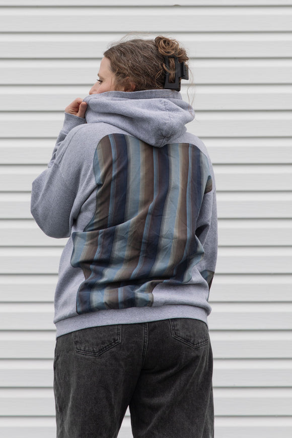 person wearing a grey hoodie with plaid inserts, upcycled in canada