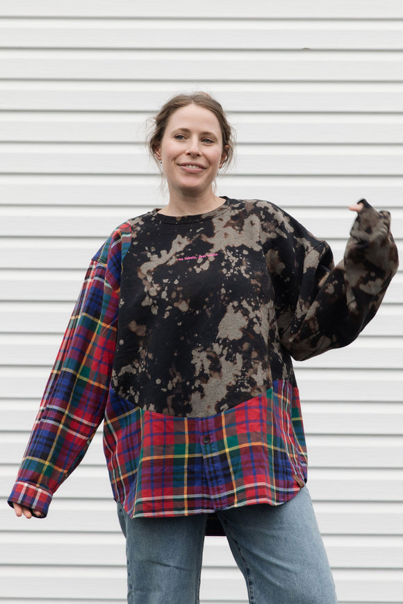 person wearing bleached sweater that is sewn together with red plaid shirt, upcycled in canada