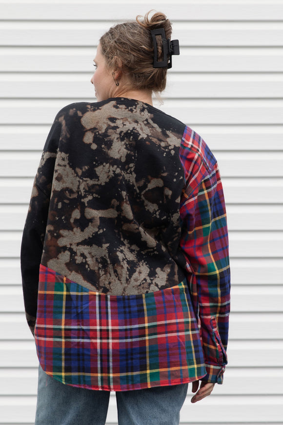 person wearing bleached sweater that is sewn together with red plaid shirt, upcycled in canada