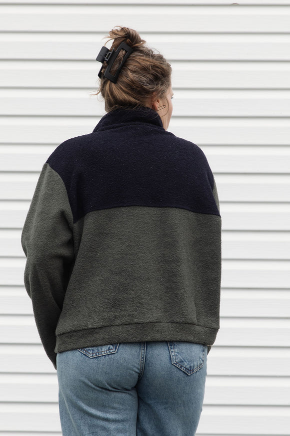 person wearing a fleecy half zip pull over, green and black, upcycled in canada