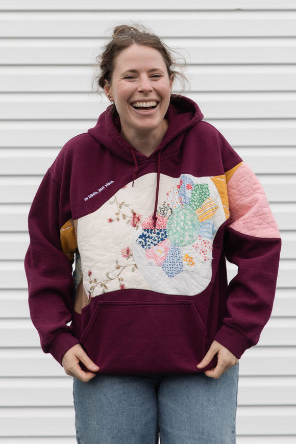 Person wearing a maroon hoodie with a colorful abstract design made with quilting scraps, upcycled in canada
