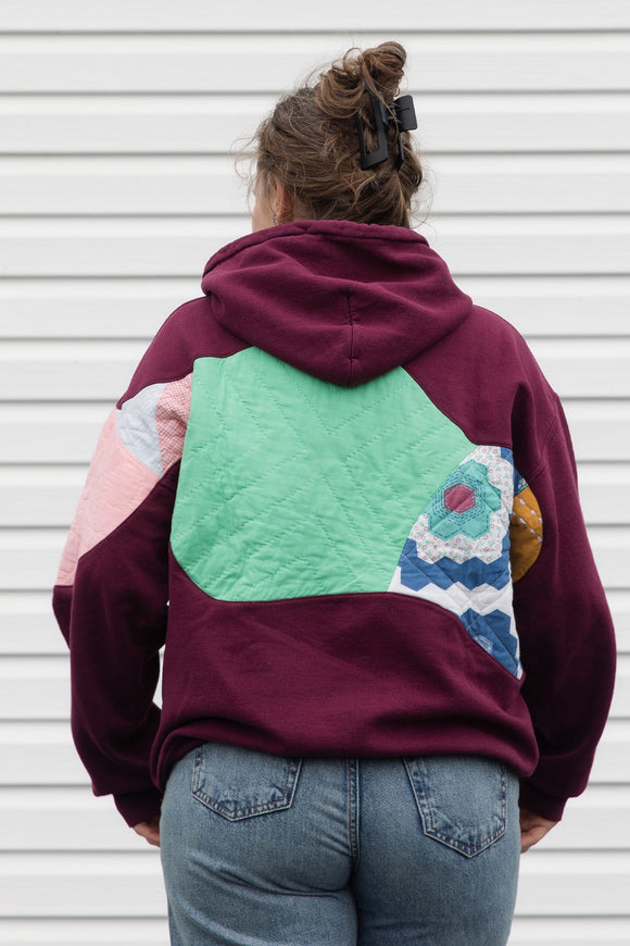 Person wearing a maroon hoodie with a colorful abstract design made with quilting scraps, upcycled in canada