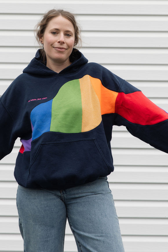 Person wearing a navy hoodie with a colourful rainbow design upcycled in canada