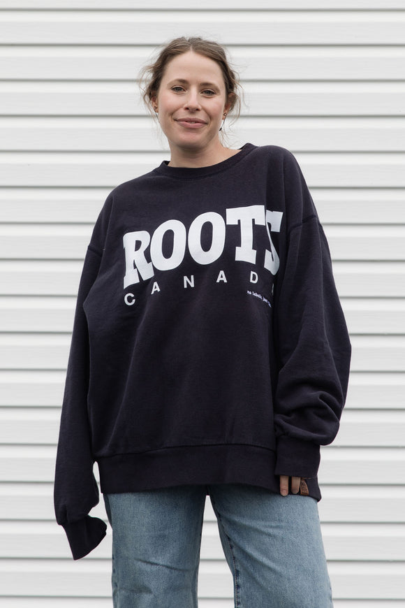 Person wearing a black 'ROOTS Canada' sweatshirt, upcycled in canada
