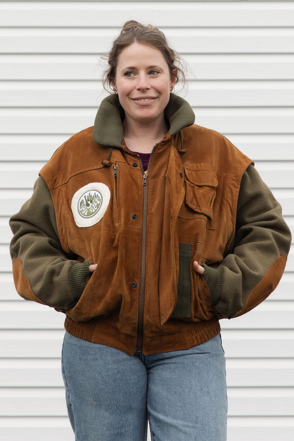 person wearing a wool & suede vintage jacket, upcycled in canada. detail shot of 'no labels, just vibes.' patch on front