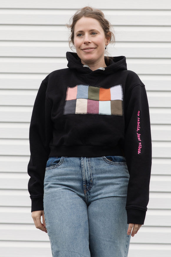 Person wearing a black hoodie with a colorful square design, upcycled in canada