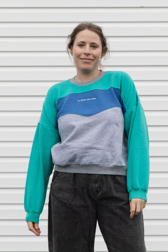 Person wearing a teal, blue and grey vintage sweater, upcycled in canada