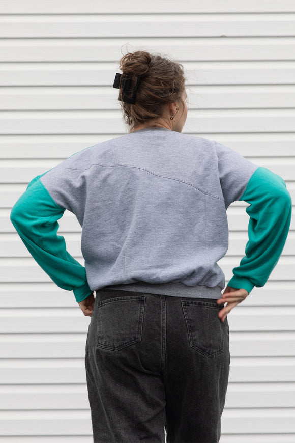 Person wearing a teal, blue and grey vintage sweater, upcycled in canada
