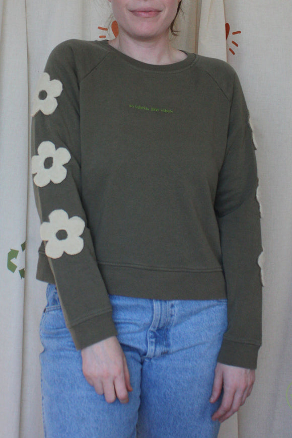 green sweater with cream flowers down the sleeves, upcycled in canada