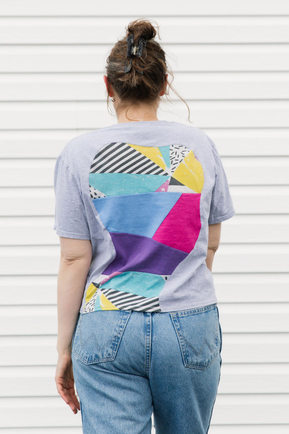 Person wearing a colorful geometric-patterned t-shirt against a white background