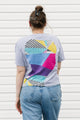 Person wearing a colorful geometric-patterned t-shirt against a white background