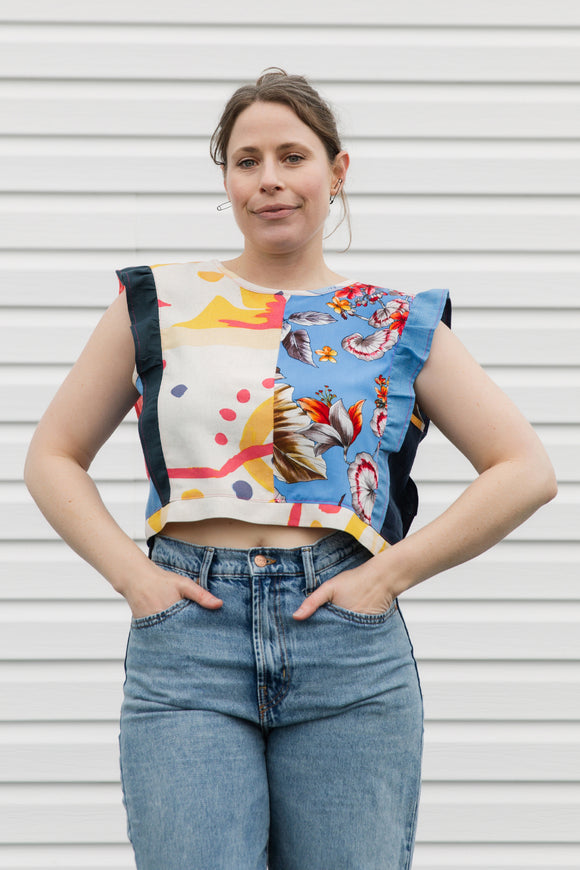 Woman wearing a colorful sleeveless top with abstract patterns against a white background