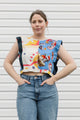 Woman wearing a colorful sleeveless top with abstract patterns against a white background