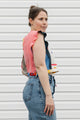Woman wearing a colorful sleeveless top and denim overalls against a white background
