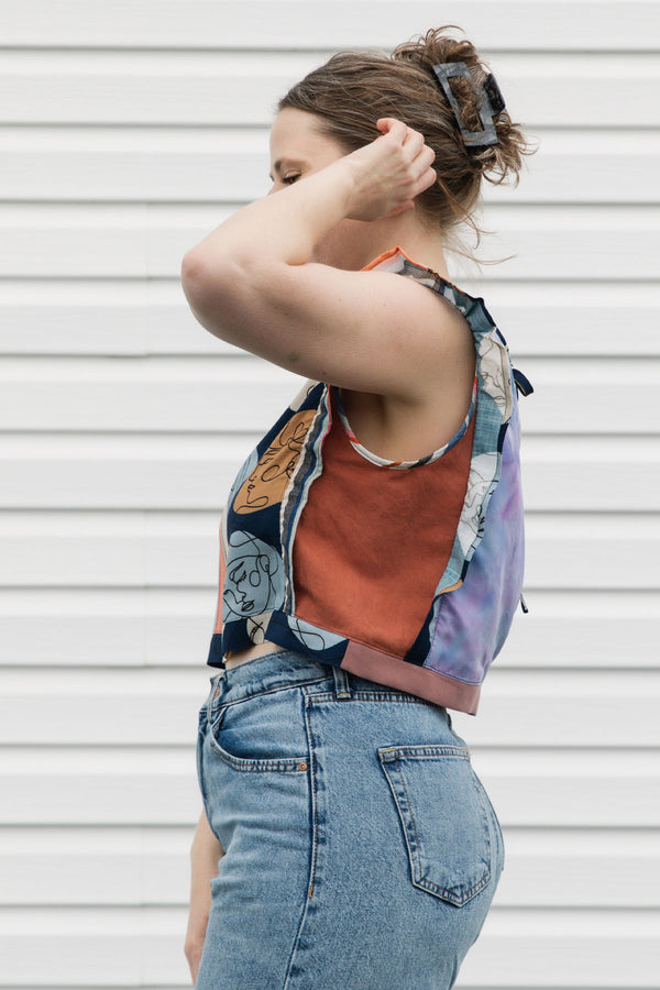 Person wearing a colorful sleeveless tank top and jeans against a white background