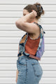 Person wearing a colorful sleeveless tank top and jeans against a white background