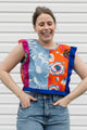 Woman wearing a colorful patchwork top with floral patterns against a plain background