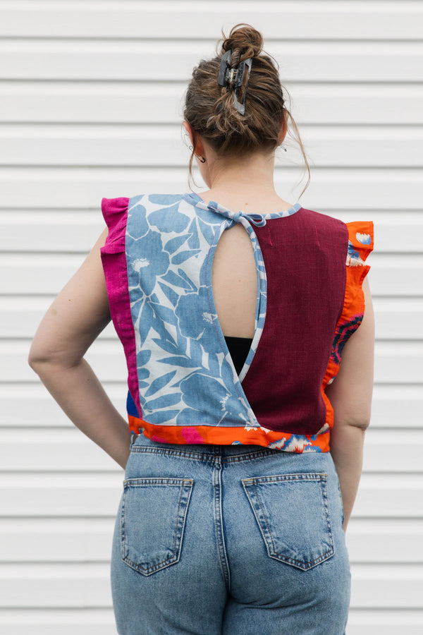 Person wearing a colorful sleeveless top with a unique pattern, standing against a plain background.