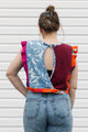 Person wearing a colorful sleeveless top with a unique pattern, standing against a plain background.