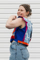 Person wearing a colorful vest over a blue shirt with a white background
