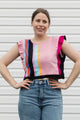 Woman wearing a colorful striped top and jeans against a plain background