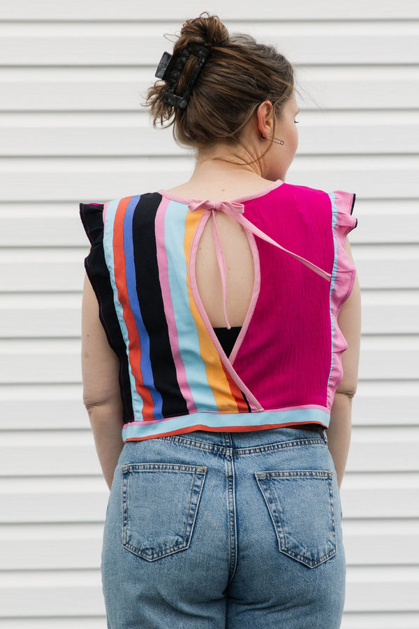 Person wearing a colorful striped top and blue jeans against a white background