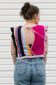 Person wearing a colorful striped top and blue jeans against a white background