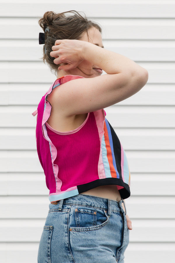 Person wearing a colorful striped tank top and jeans against a white background