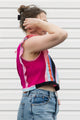 Person wearing a colorful striped tank top and jeans against a white background