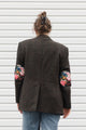 person wearing a brown blazer with floral elbow patches, upcycled in canada
