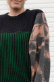 person wearing upcycled sweater with black and green knit and bleached sleeves, featuring 'no labels, just vibes.' embroidered on the sleeve, upcycled in canada