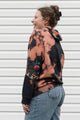 perosn wearing bleached hoodie with floral elbow patches, upcycled in canada
