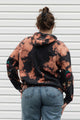 perosn wearing bleached hoodie with floral elbow patches, upcycled in canada