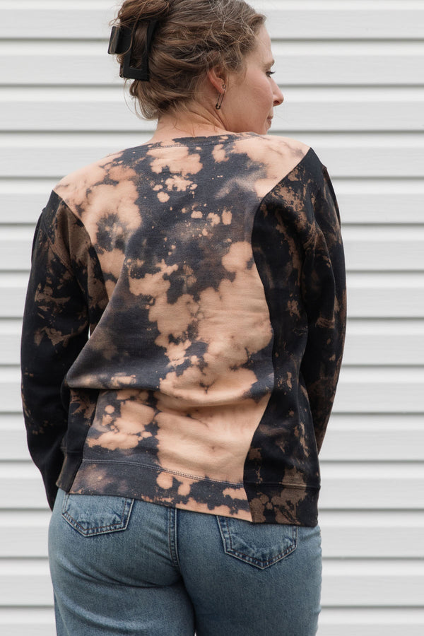 person wearing bleached sweater, upcycled in canada and featuring the 'no labels, just vibes.' embroidery