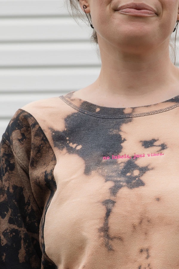 person wearing bleached sweater, upcycled in canada and featuring the 'no labels, just vibes.' embroidery